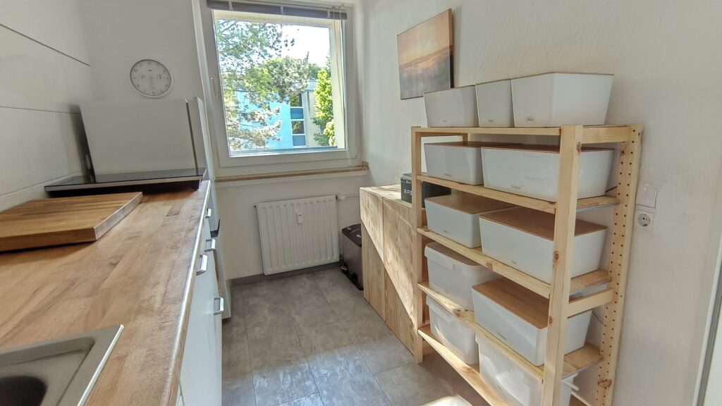 Blick auf ein Holzschrank und ein Regal mit mehreren weißen Boxen